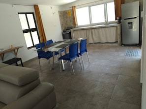 A modern kitchen with a stainless steel refrigerator, a gas stove, and a window with curtains.