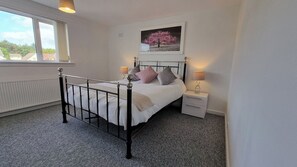 Une chambre à coucher avec un lit, des tables de chevet, une fenêtre et un tableau au mur.