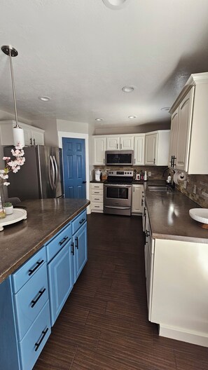A modern kitchen with stainless steel appliances, blue cabinetry, and a central island. - Beautiful 5-bedroom house with a beautiful mountain views. (North Ogden)