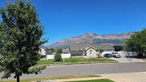 A residential street with houses, a tree, and mountains in the background. - Beautiful 5-bedroom house with a beautiful mountain views. (North Ogden)