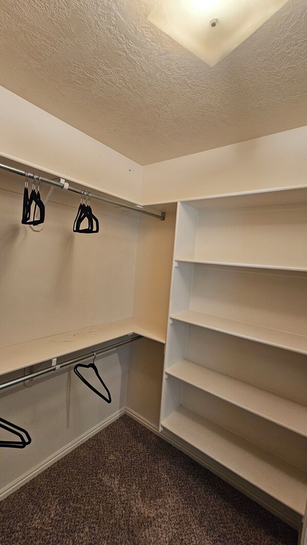 A walk-in closet with open shelving and a metal rod for hanging clothes. - Beautiful 5-bedroom house with a beautiful mountain views. (North Ogden)