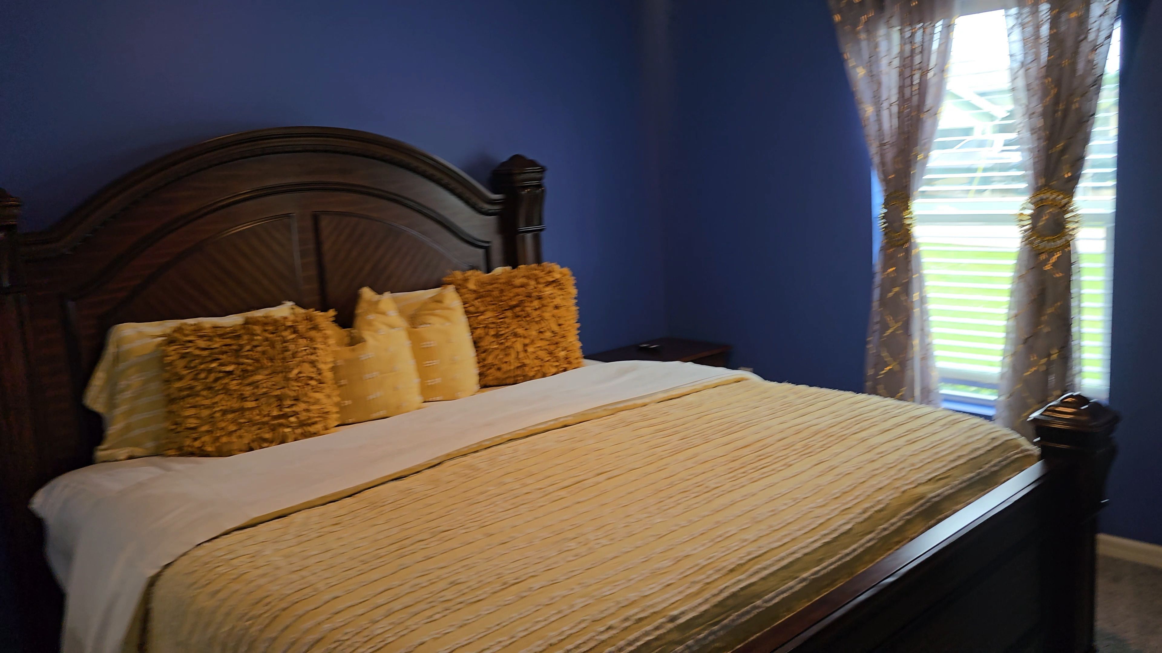 Ein Bett mit Holz Kopfteil, weißer Bettwäsche und vielen Kissen.