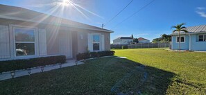 A residential property with a well-maintained lawn, a house with a front porch, and a clear sky.