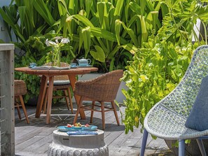 An outdoor seating area with wicker furniture, a round table, and chairs. - NoKu Beach House - Beachfront 6BR Seminyak Villa, Sunsets & Full Staff (Badung)
