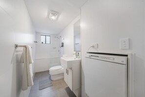 Et moderne badeværelse med toilet, håndvask og brusebad.