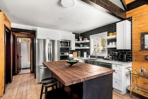 A modern kitchen with stainless steel appliances, wooden flooring, and a central island with stools. - 8 min to Breck DT•Steps to Stream•Hottub/Sauna (Breckenridge)
