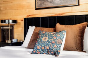 Een bed met een zwart hoofdeinde, twee bruine kussens en een decoratief blauw kussen.