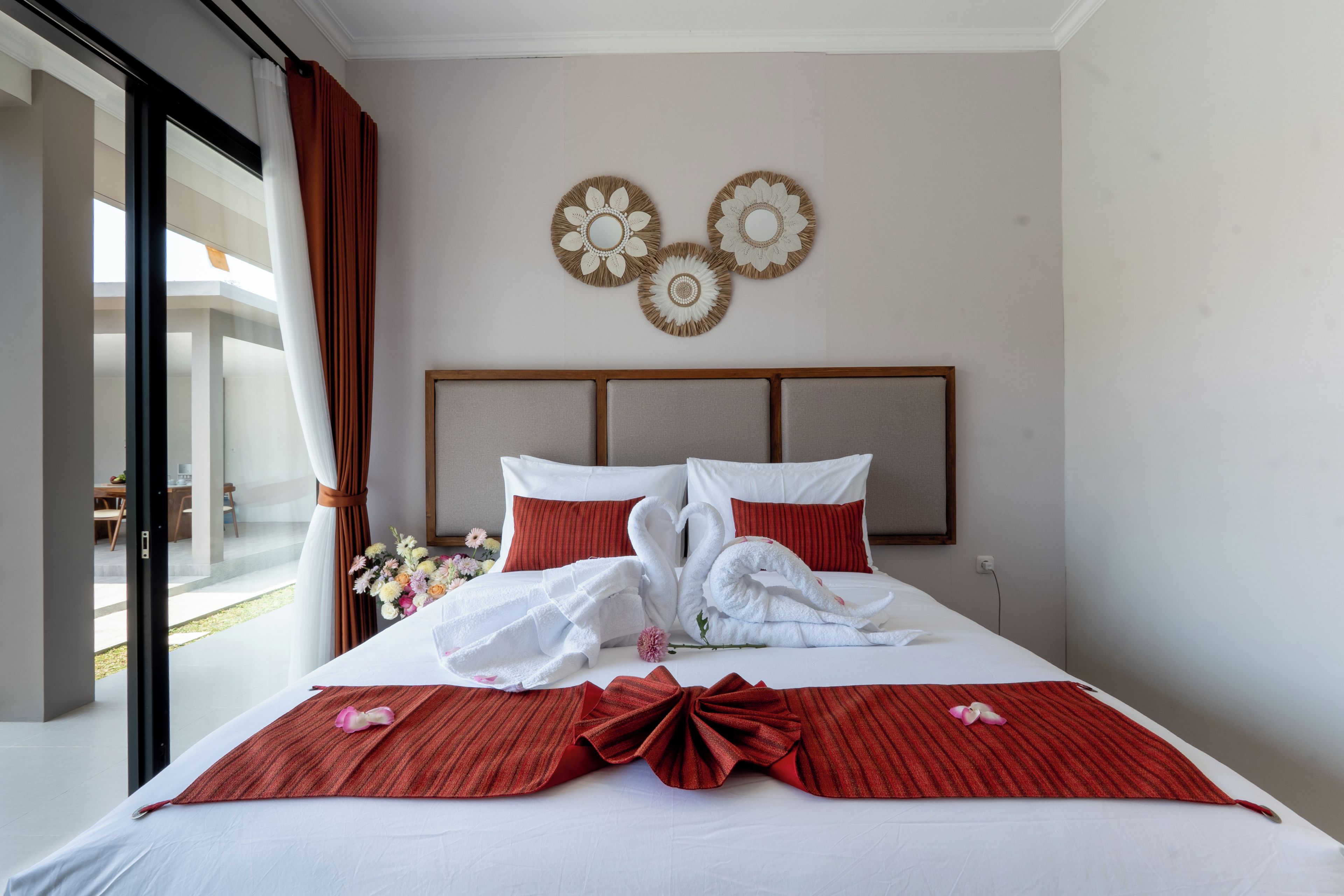 A hotel room with a bed, a view of the outdoors, and decorative wall art.