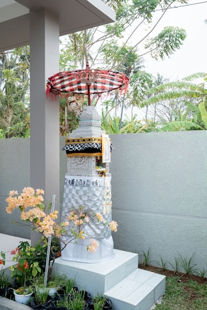 Una estructura escalonada con un parasol a cuadros, rodeada de plantas tropicales y una pared gris.