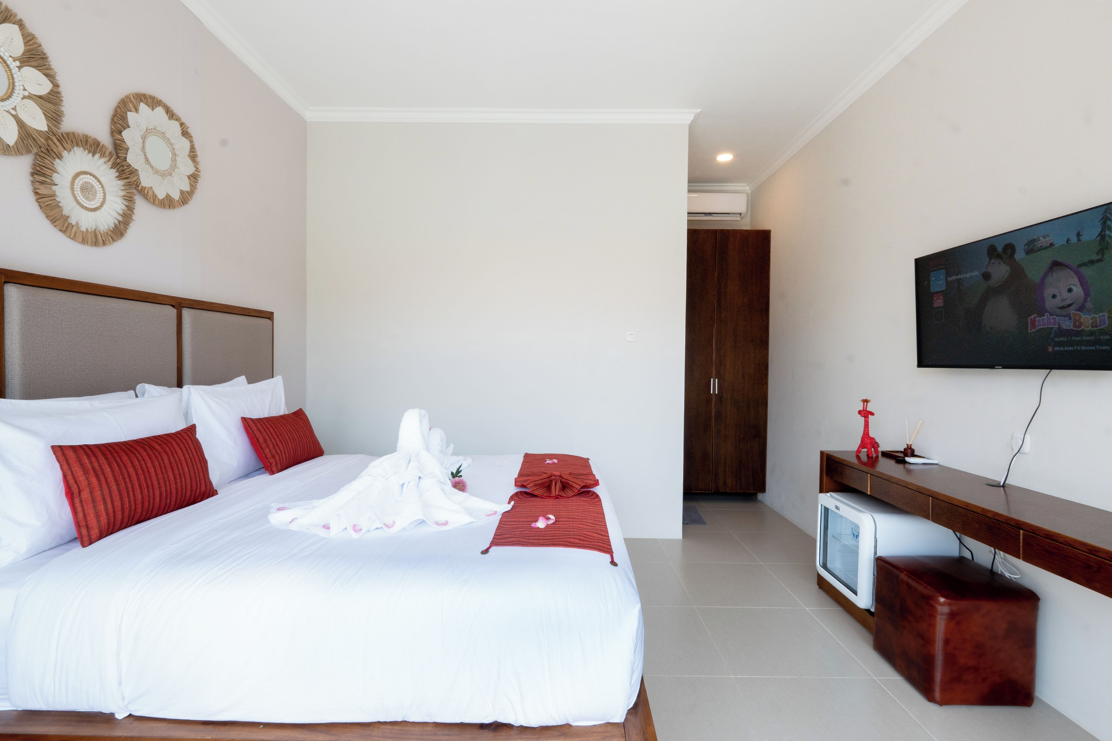 A hotel room with a large bed, a television, and a wooden cabinet.