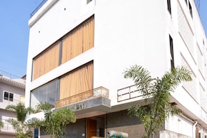 Un edificio moderno con fachada plana, ventanas grandes y un balcón con barandilla decorativa.