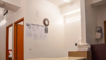 Un baño con puerta de madera, un reloj colgado en la pared y una pila de toallas.