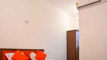 Una habitación de hotel con cama, armario y aire acondicionado.