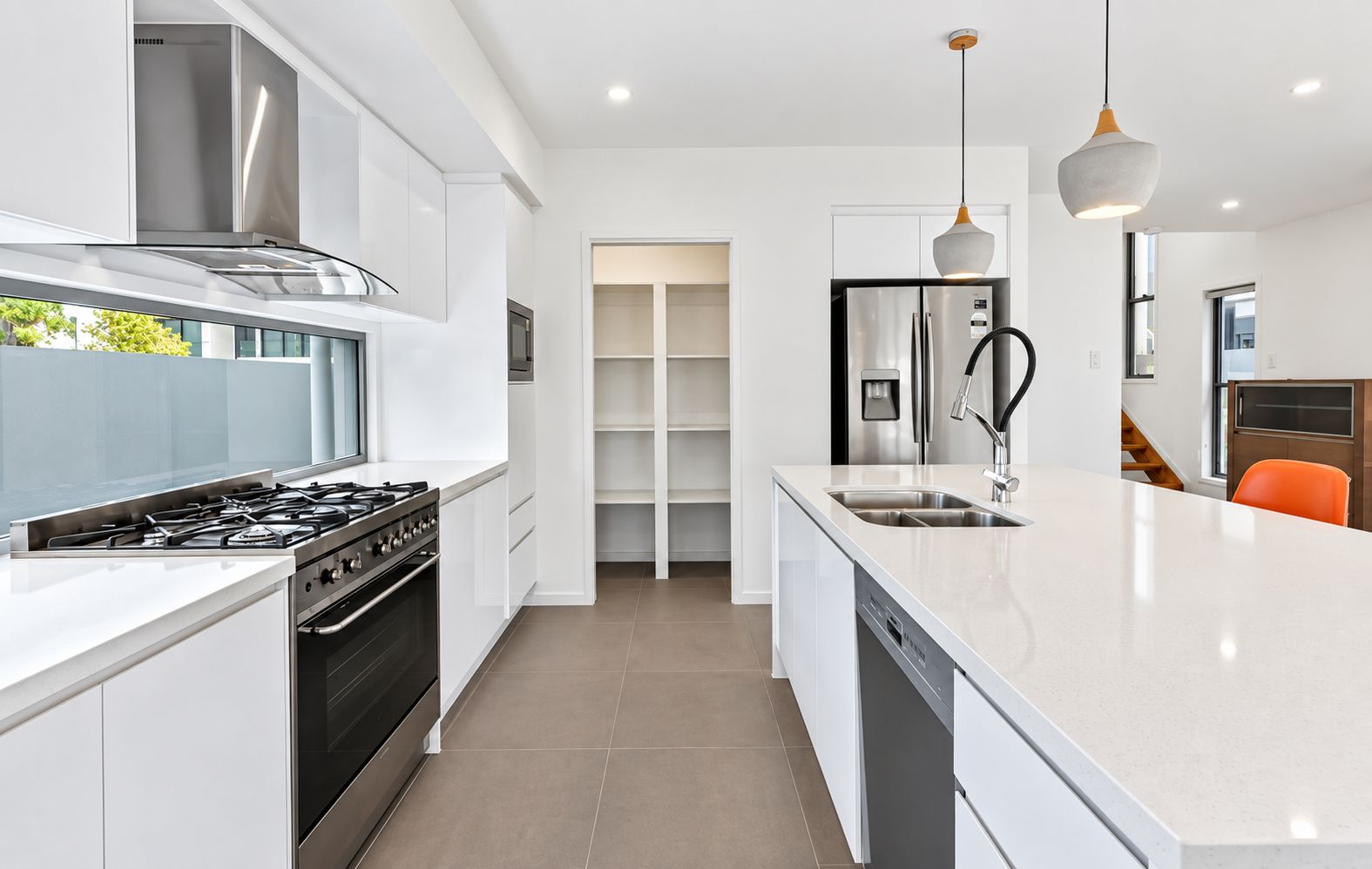 A modern kitchen with a gas stove, stainless steel appliances, a dishwasher, and a large island with a sink.
