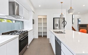 A modern kitchen with a gas stove, stainless steel appliances, a dishwasher, and a large island with a sink.