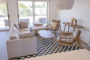 Ein modernes Wohnzimmer mit Schachbrettfußboden, einer Sofagarnitur, einem Couchtisch und einem Sessel.
