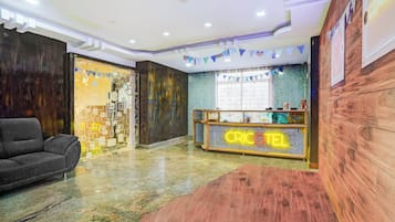 Un área de recepción con un mostrador de madera identificado con 'CRICKET' y un sofá gris.
