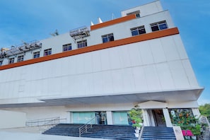 A modern building with a flat facade, a set of stairs leading to the entrance, and a clear sky above.