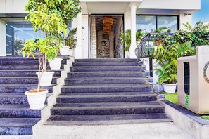 A set of stone steps leading to a building entrance with a mural, surrounded by potted plants. - LIVING SUITES (Bangalore)