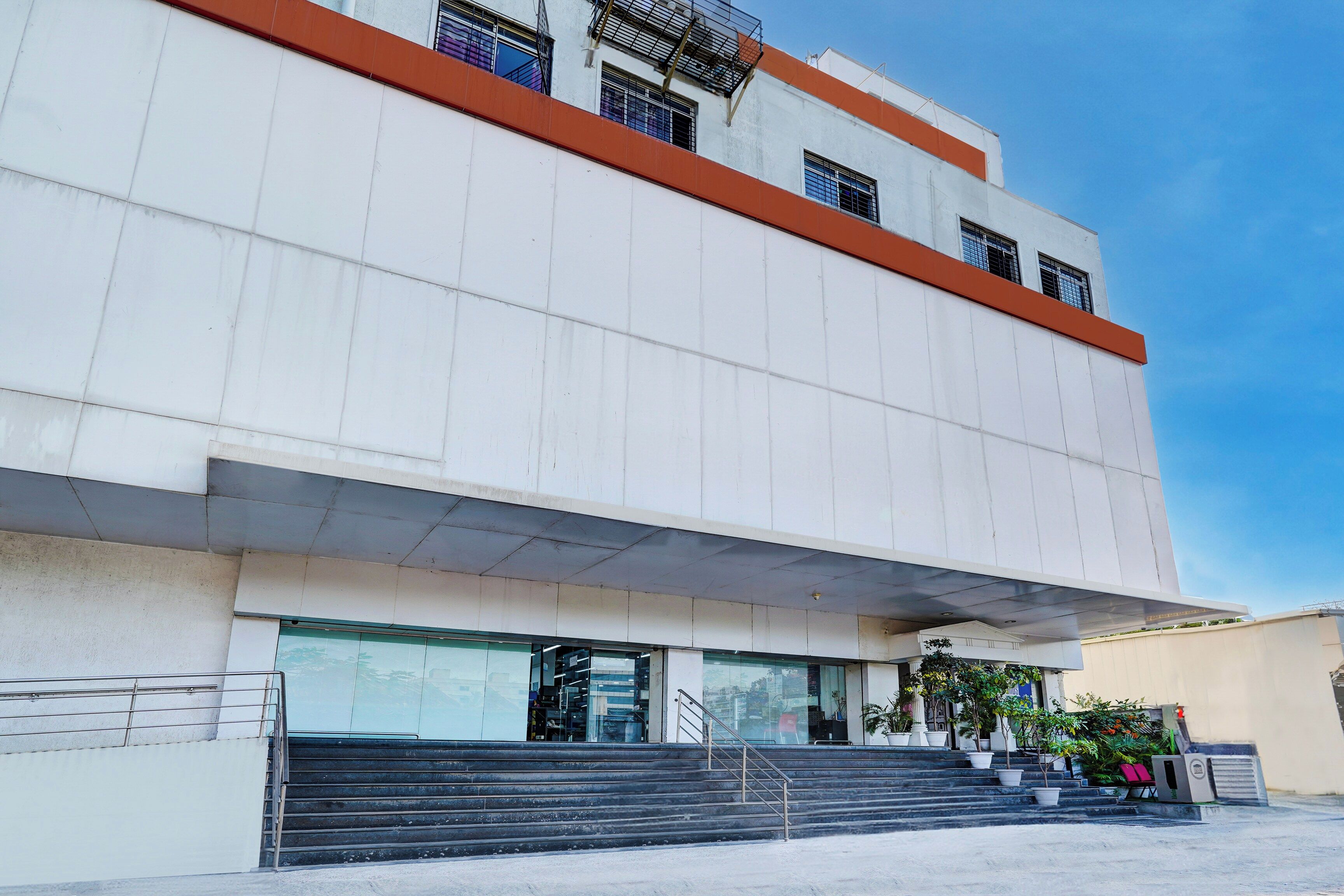 A modern building with a flat facade, large windows, and a set of stairs leading to the entrance.