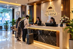 Un mostrador de recepción de hotel con encimera de mármol, un reloj y un cartel que dice 'HOTEL SUNRISE'.