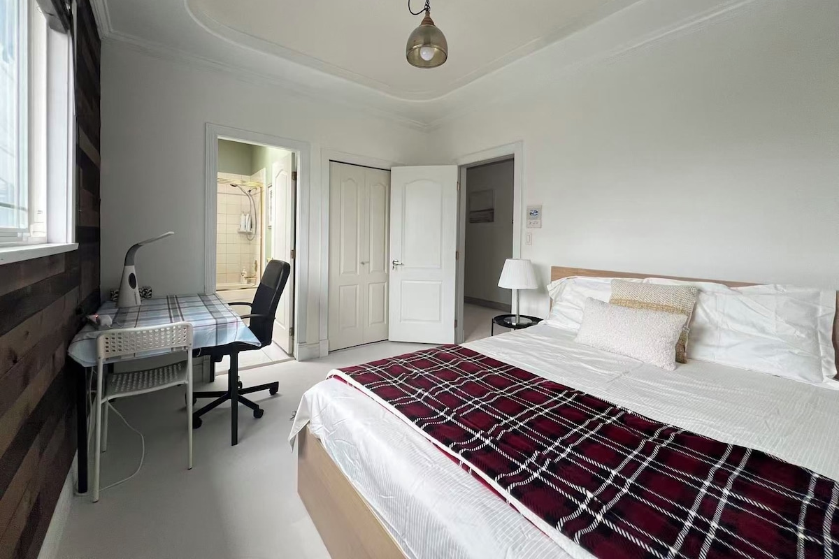 A bedroom with a bed, a desk, a chair, a lamp, and a ceiling light.