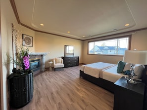 A bedroom with a bed, dresser, nightstand, and a fireplace. - Haidian Mama Garden Suite (Richmond)