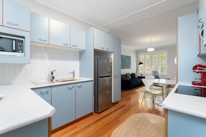 A modern kitchen with light blue cabinets, a stainless steel refrigerator, and a microwave.