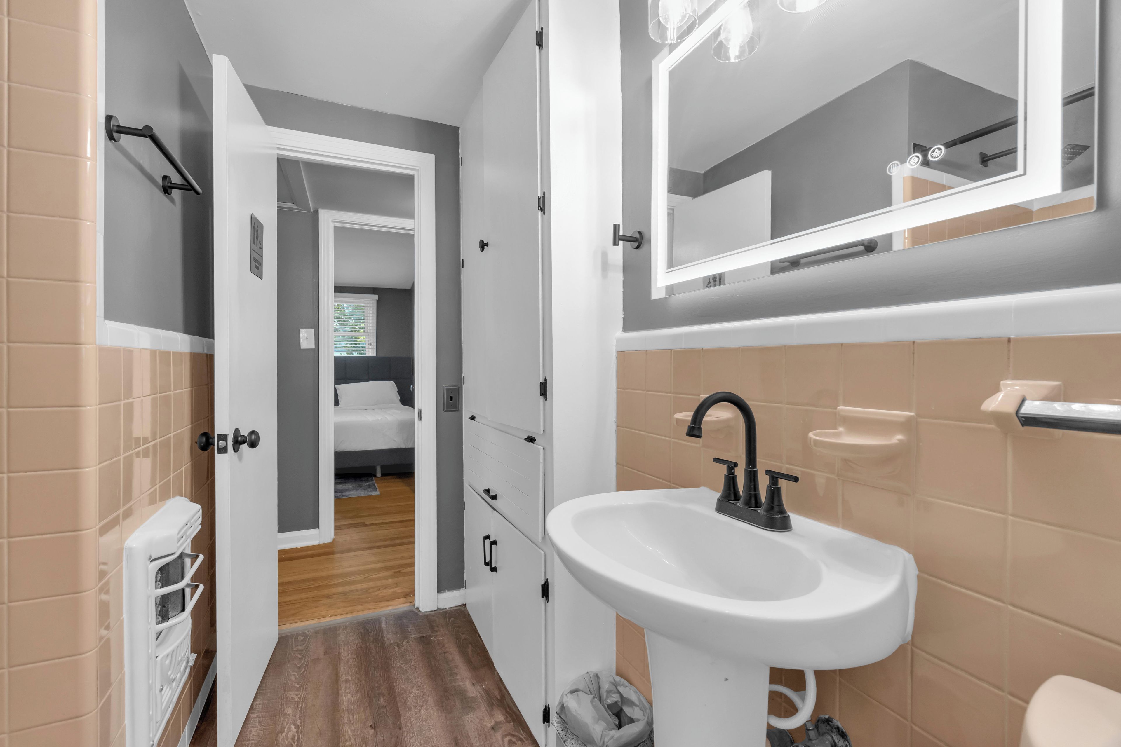 Un baño moderno con un lavabo blanco, un espejo y una zona de ducha.