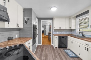 A modern kitchen with white cabinets, a wooden countertop, and a built-in oven. - Midtown Executive | Work & Extended Stays | 4 Beds (Montgomery)