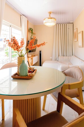 A modern living room with a glass-top dining table, a sofa, and a chandelier. - Puerto Plata City Stay (Puerto Plata)