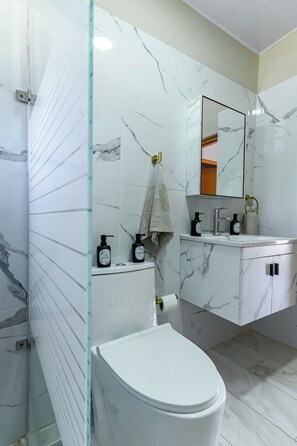 Et moderne badeværelse med toilet, vask og spejl.