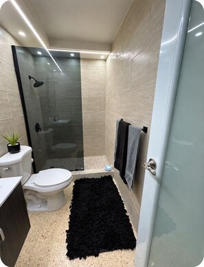 A modern bathroom with a toilet, sink, and shower area. - 3-bedroom house in beautiful Luquillo with cool AC breeze (Luquillo)