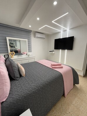 A bedroom with a bed, a large mirror, a flat-screen TV, and recessed ceiling lighting. - 3-bedroom house in beautiful Luquillo with cool AC breeze (Luquillo)