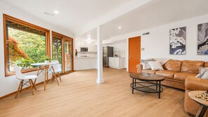 A spacious living area with a dining table, a sofa, and a coffee table. There is a kitchen in the background. - The PNW Haven - Cozy 1-br Bottom unit in amazing Seattle neighborhood with AC. (Seattle)