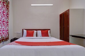 A hotel room with a bed, a nightstand, a telephone, a wardrobe, and a mirror.