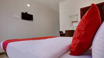 A hotel room with a bed, a television mounted on the wall, and a mirror above a wooden door.