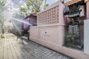 Der Eingang eines Boutique-Hotels mit dekorativer Fassade, einem gefliesten Weg und Blick auf die Straße.