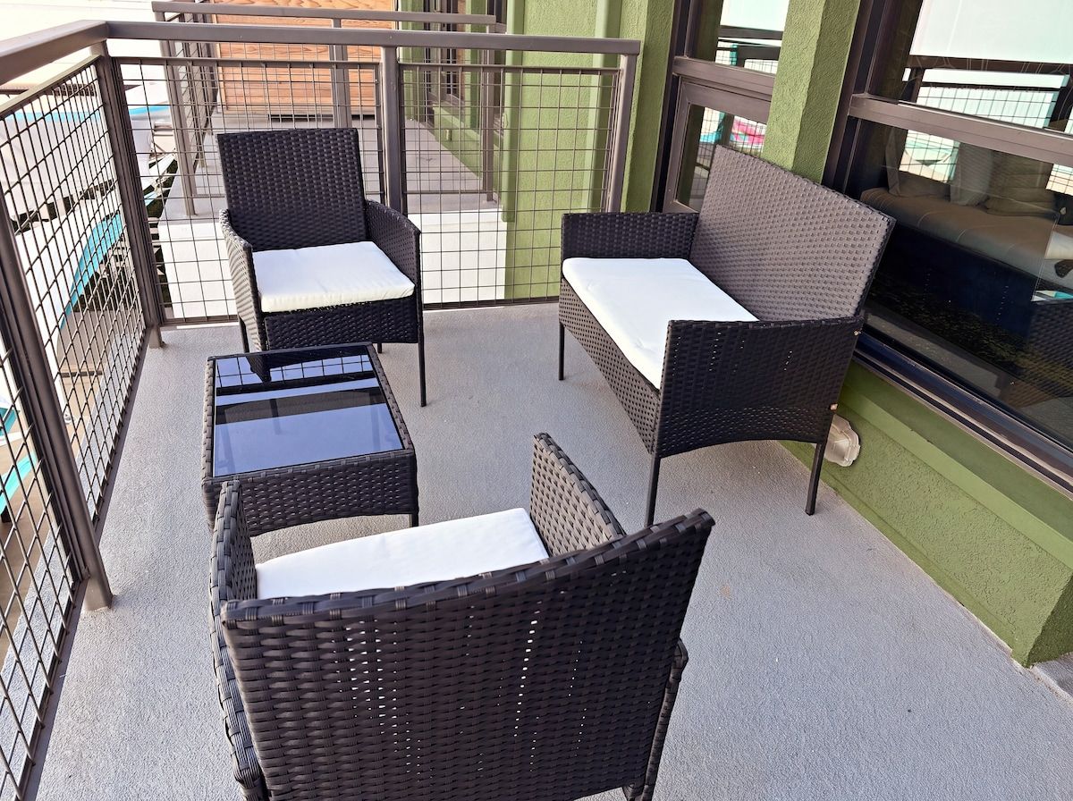 Ein Balkon mit Korbmöbeln, darunter zwei Stühle und ein Tisch.
