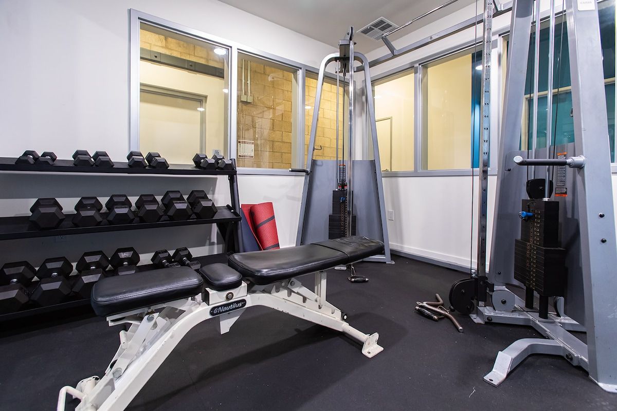 Ein Fitnessstudio mit Gewichten, Kurzhanteln und Bänken.