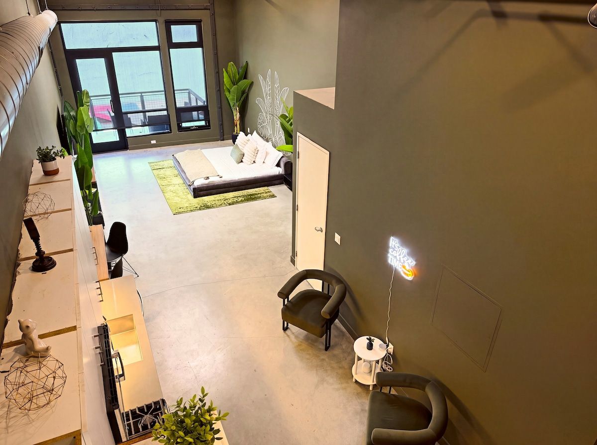 A spacious living area with a sofa, two armchairs, a coffee table, and a large window offering a view of the outdoors.