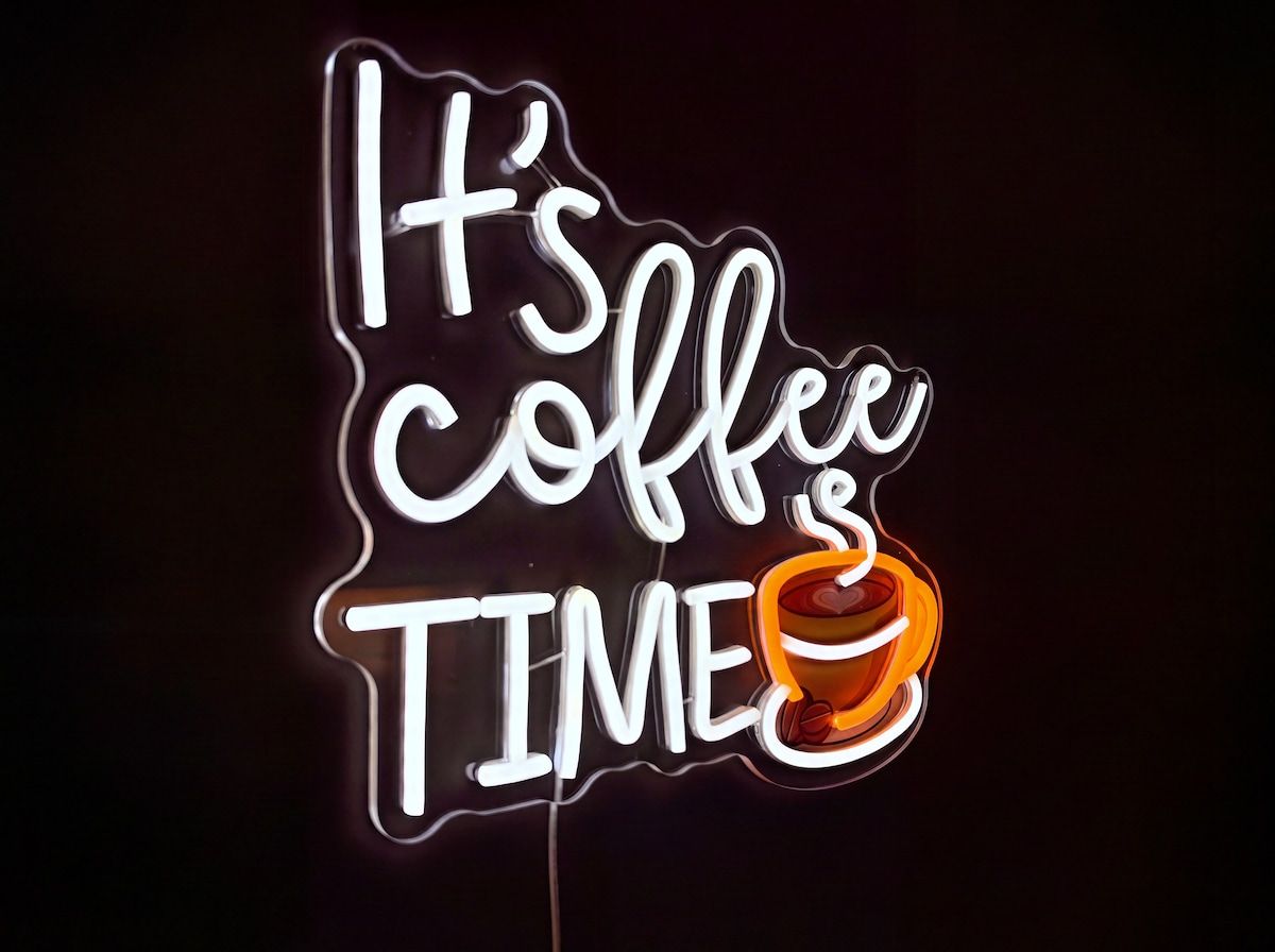 A neon sign with the text 'It's coffee time' and a coffee cup icon.