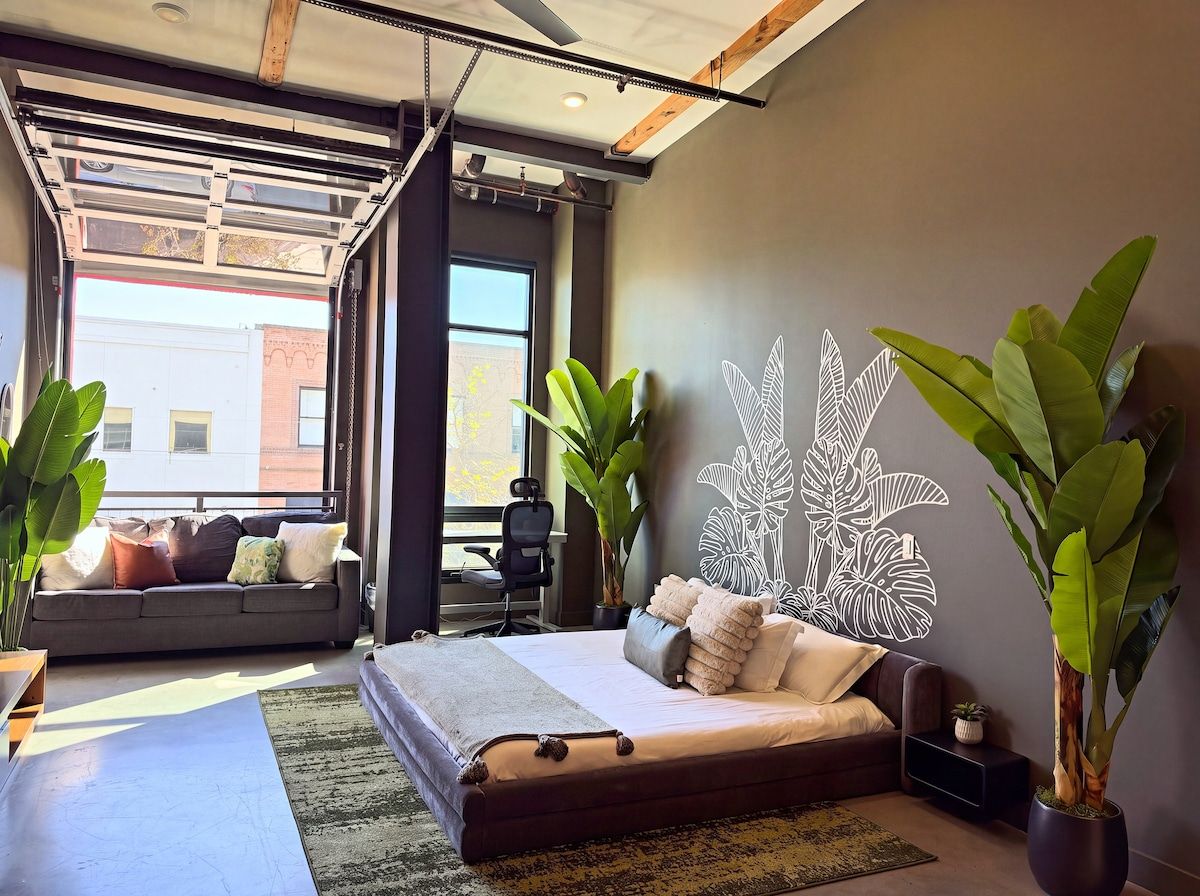 A modern bedroom with a bed, a sofa, and a large wall art piece.