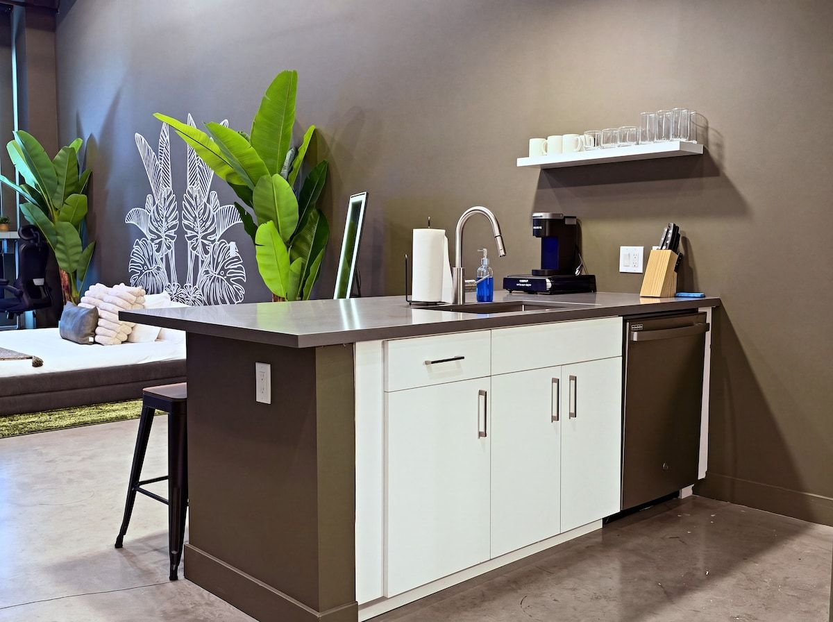 Una cocina moderna con lavavajillas integrado, una cafetera y una zona de bar con taburetes.