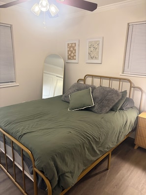 Quarto com cama, mesa de cabeceira, espelho e obras de arte nas paredes.