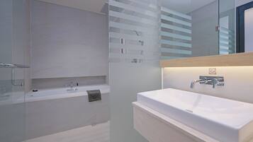 Een moderne badkamer met een grote spiegel, een wit wastafelmeubel en een douchecabine met glazen wanden.