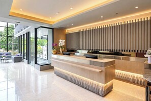 Un área de recepción moderna con un mostrador de madera, divisiones de vidrio y vistas al exterior.