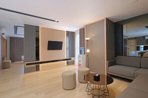 Ein modernes Wohnzimmer mit Flachbildfernseher an der Wand, einer Couch, einem Couchtisch und einem Wasserspender.