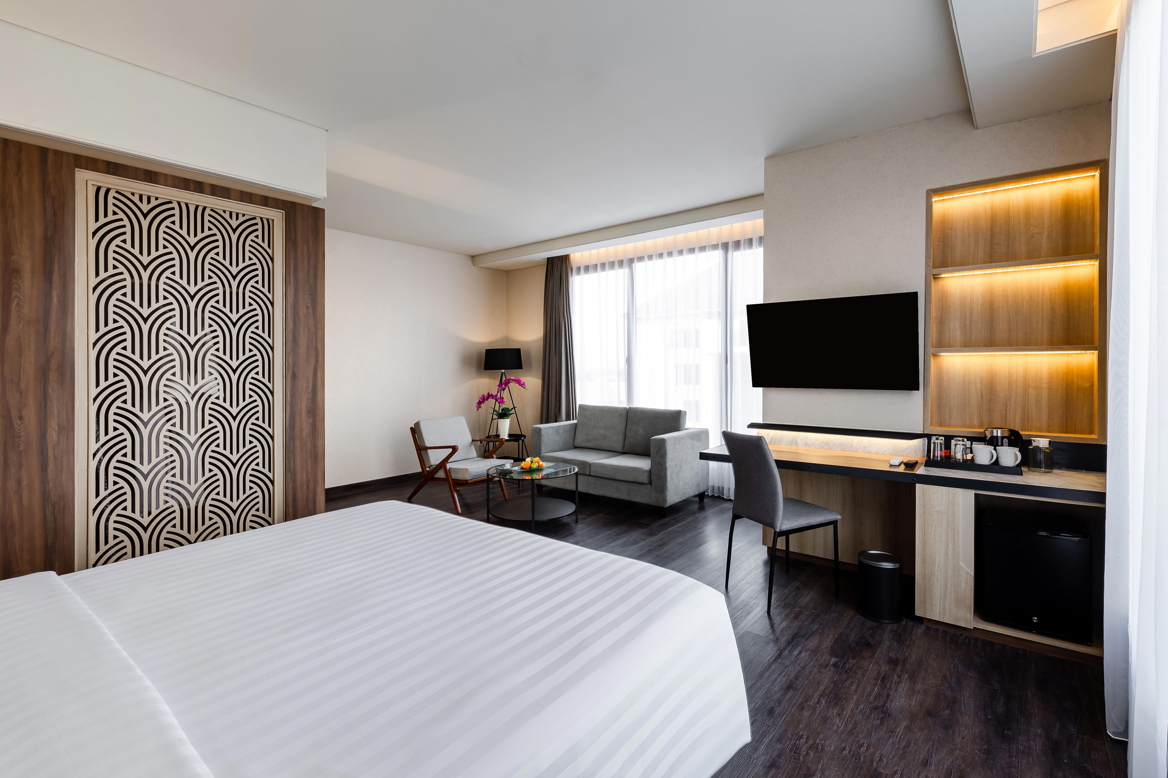 Una habitación de hotel con cama, escritorio, sofá, televisor y una pequeña cocina.