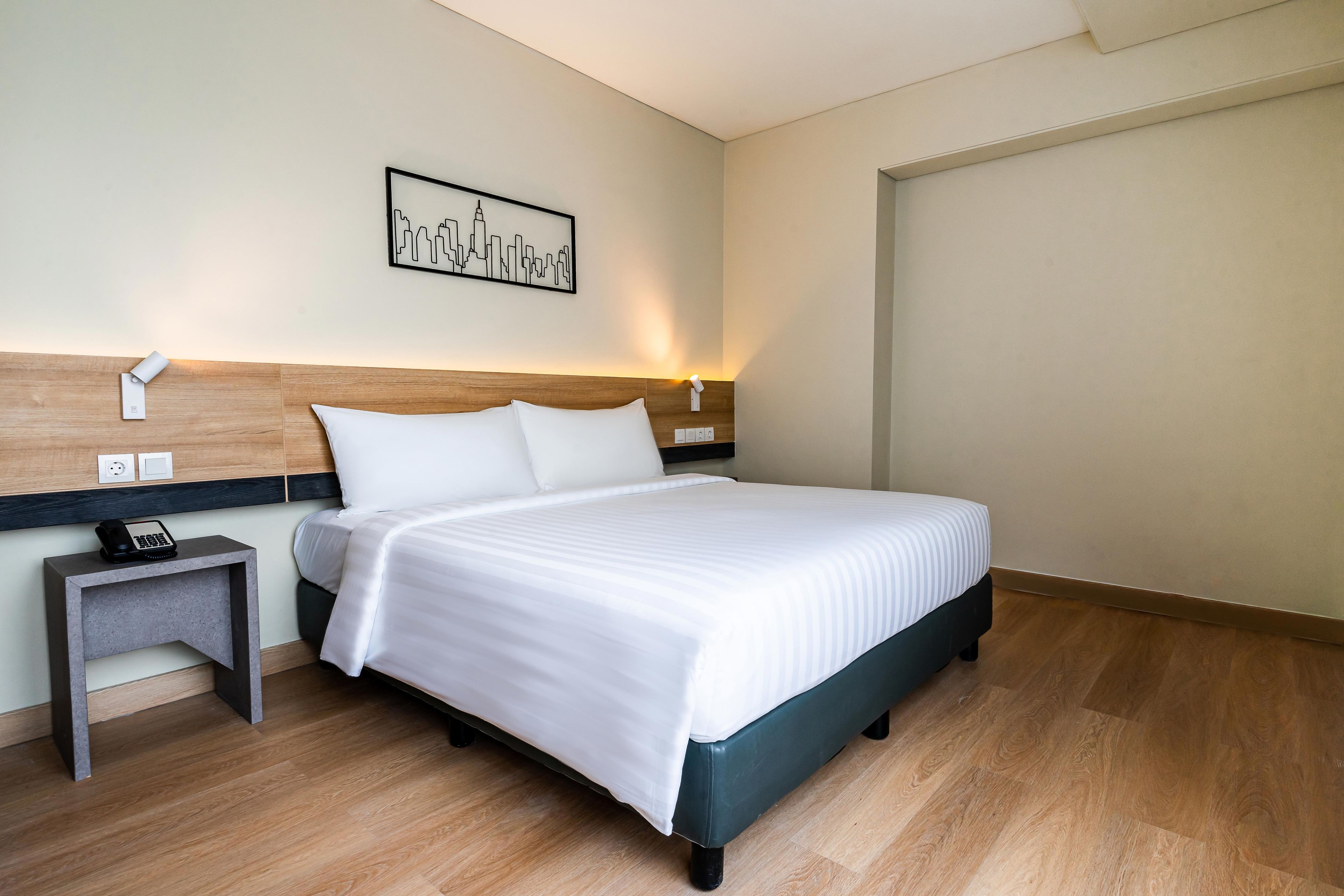 Ein Hotelzimmer mit Bett, Nachttisch und Wandleuchte.